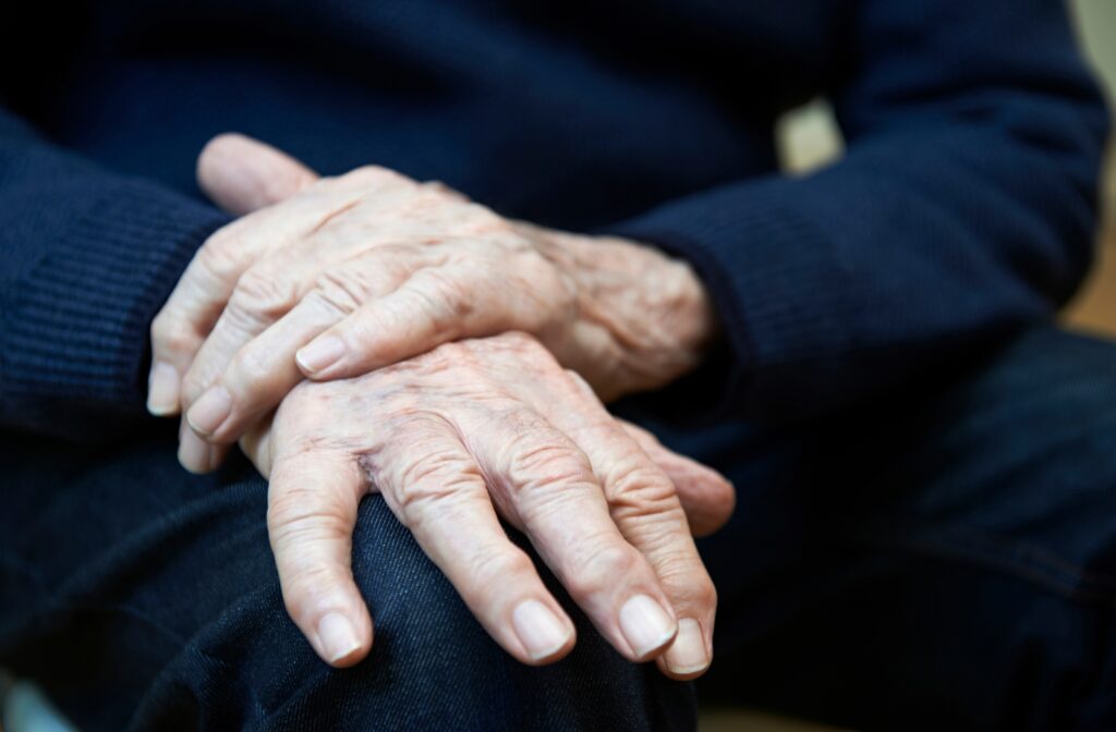 A close up of a seniors hand as he grips it with his other hand to limit the shaking due to Parkinson’s