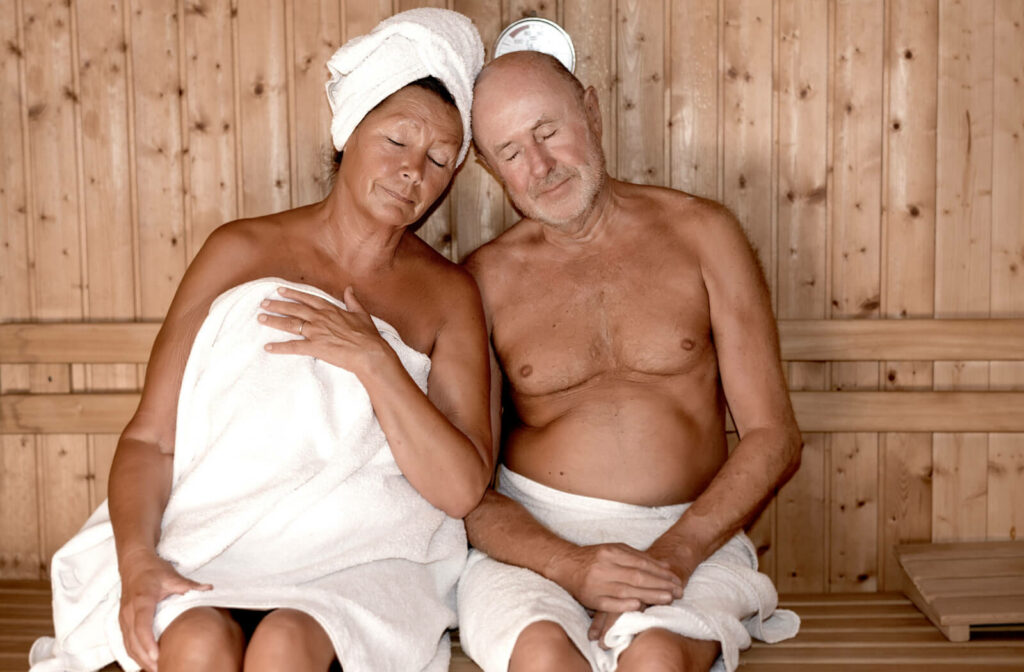 An older adult couple relaxing in a sauna room.