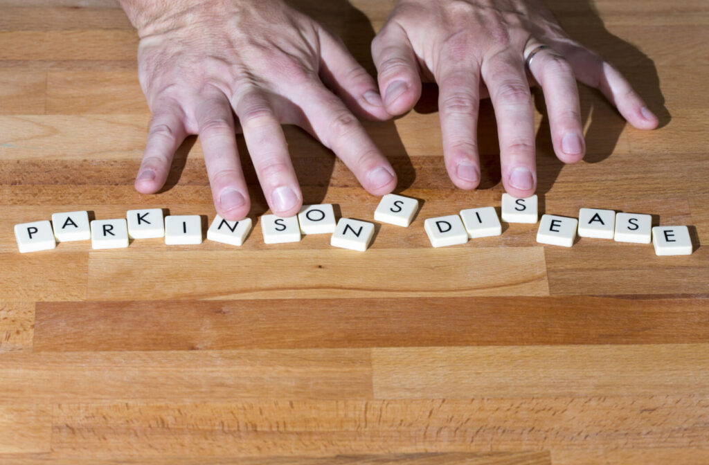 An older adult man’s hand with Parkinson's disease text on a wooden table